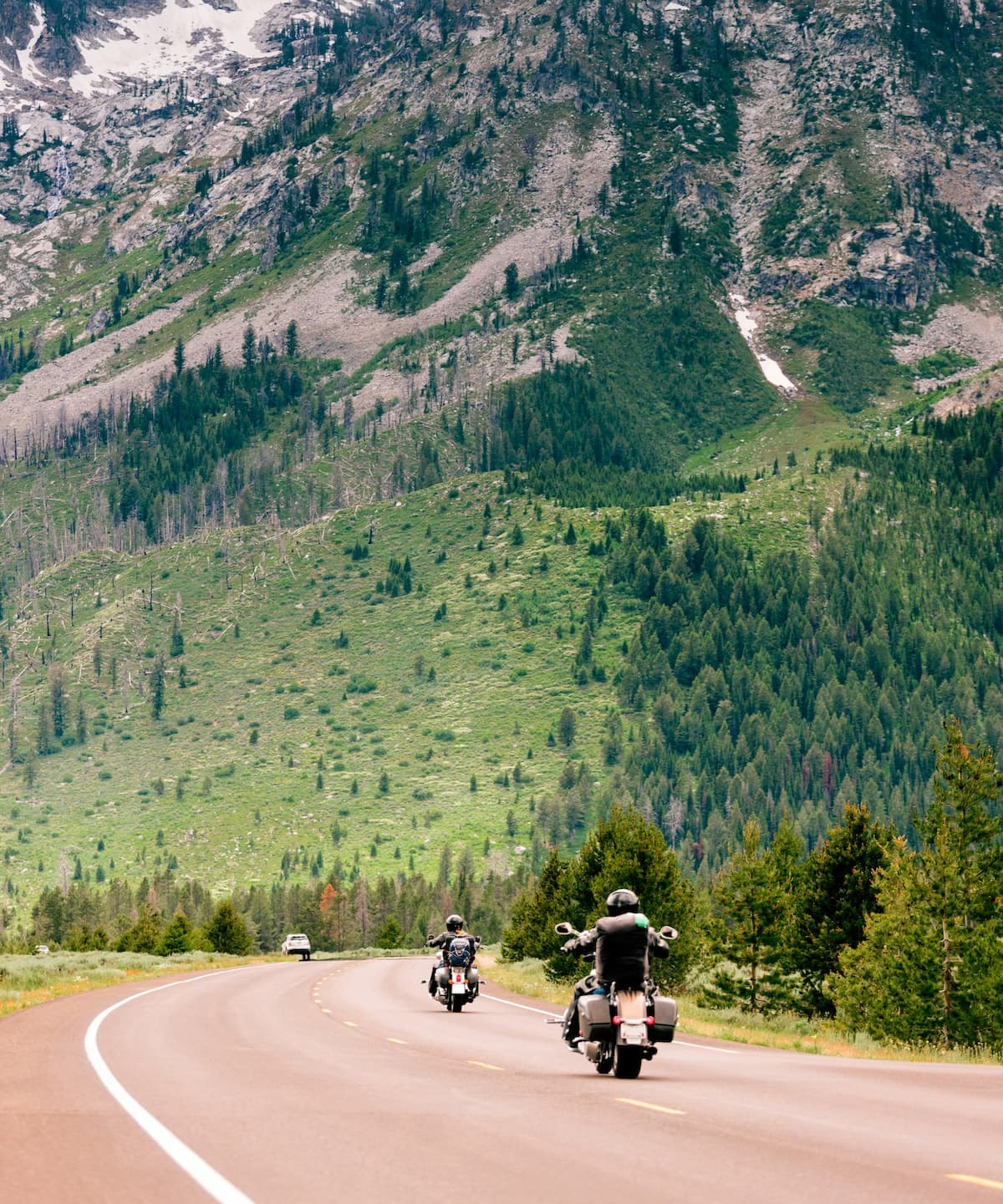 Group of motorcyclists riding on a scenic road with mountains in the background