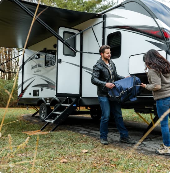 A woman sitting in a camper van holding a toddler while laughing with a man