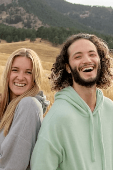 Two people laughing together in mountain setting