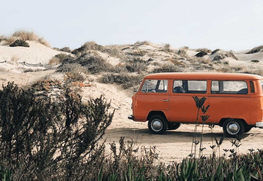 Classic orange VW bus against sand dunes