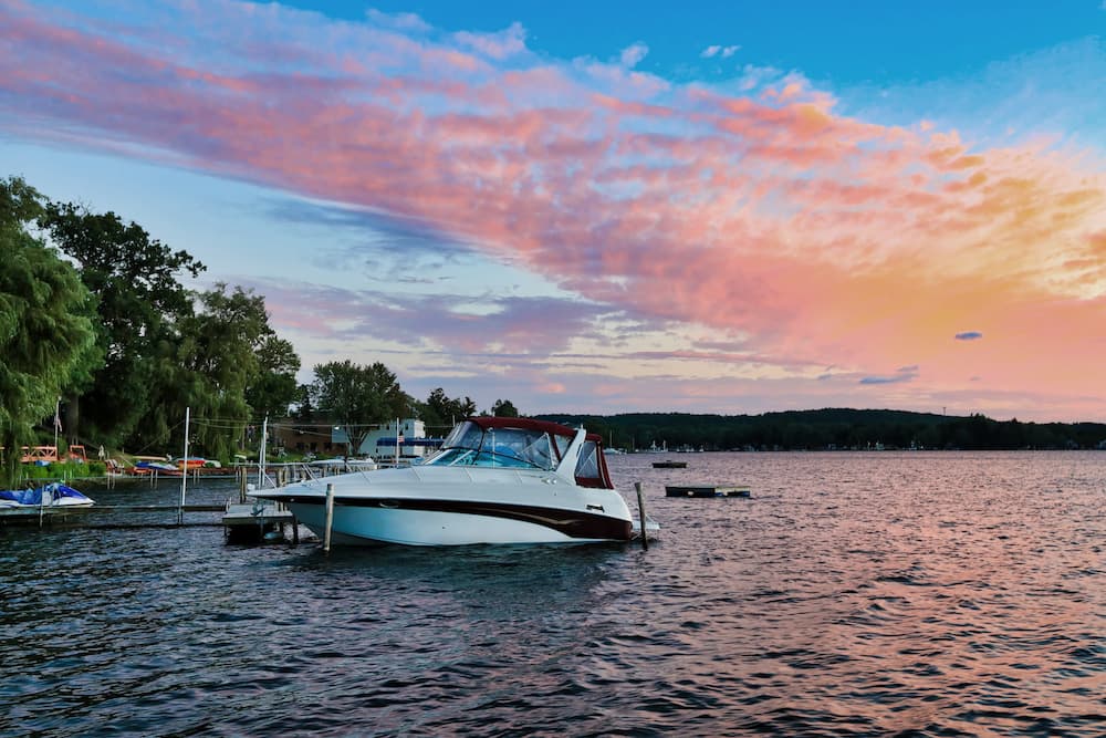 White powerboat docked at marina during golden hour sunset