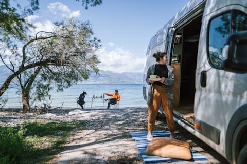 RV campsite setup beside pristine lake with awning extended for outdoor living